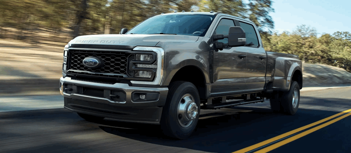 Ford Super Duty F-250 2026 gris en conduite sur route, camion lourd offrant de fortes capacités de remorquage.
