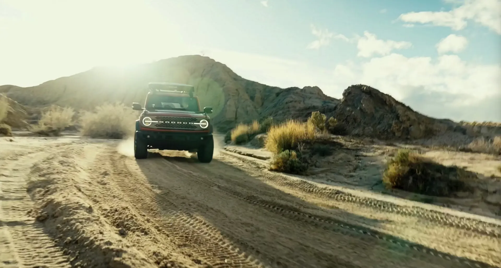 Ford Bronco 2026 roulant sur un sentier sablonneux en montagne.