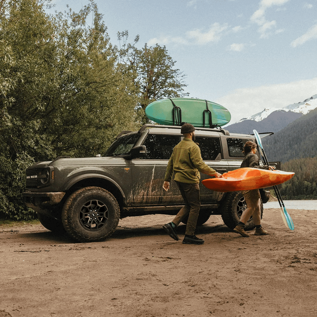 Ford Bronco 2026 avec toit amovible transportant des kayaks en montagne.