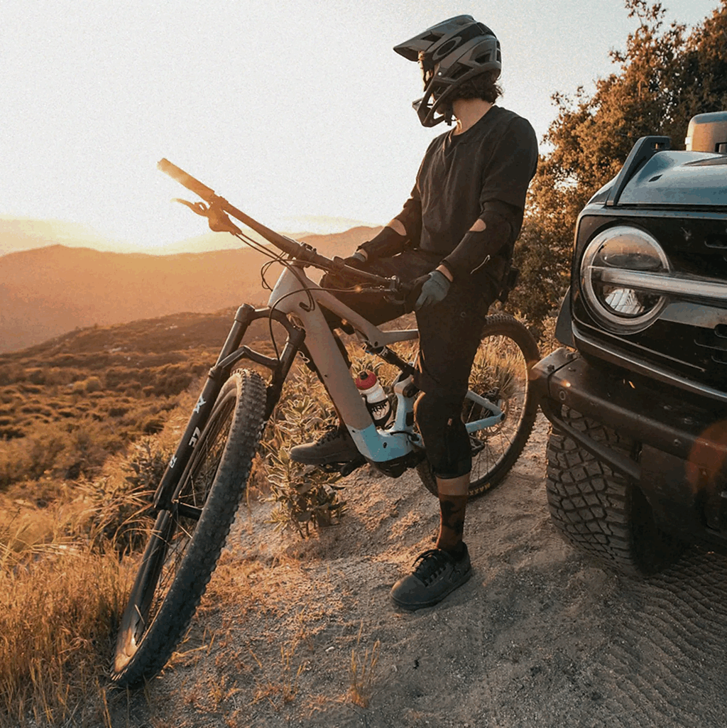Cycliste de montagne près d’un Ford Bronco 2026 au coucher du soleil.