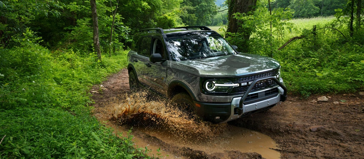 Ford Bronco Sport 2026 en conduite hors route sur un sentier boueux en forêt.