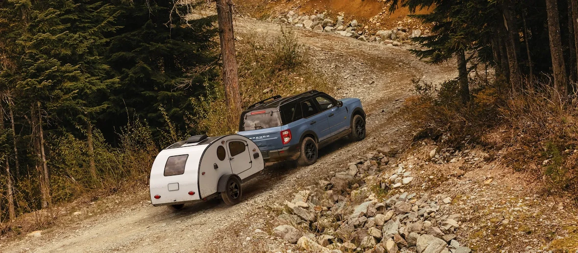Ford Bronco Sport 2026 remorquant une roulotte sur un chemin de montagne.