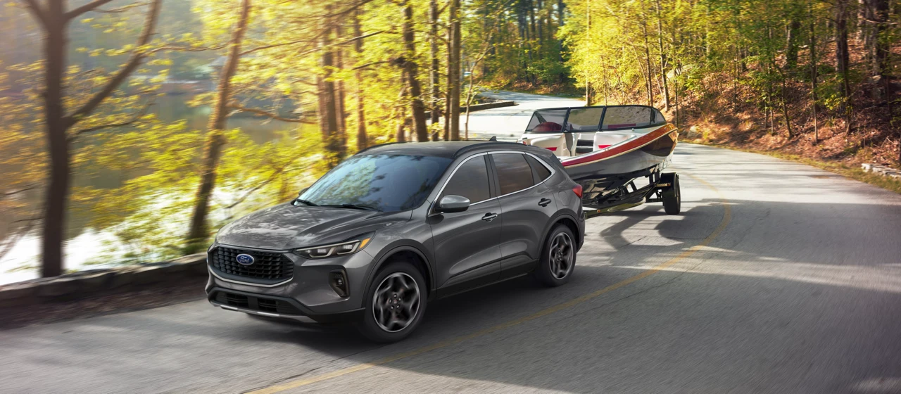 Ford Escape 2026 remorquant un bateau sur une route en forêt.