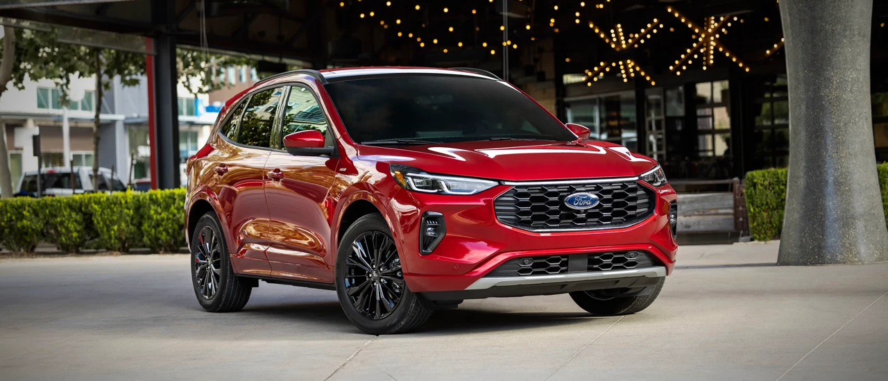 Ford Escape hybride 2026 rouge présenté devant un bâtiment moderne.