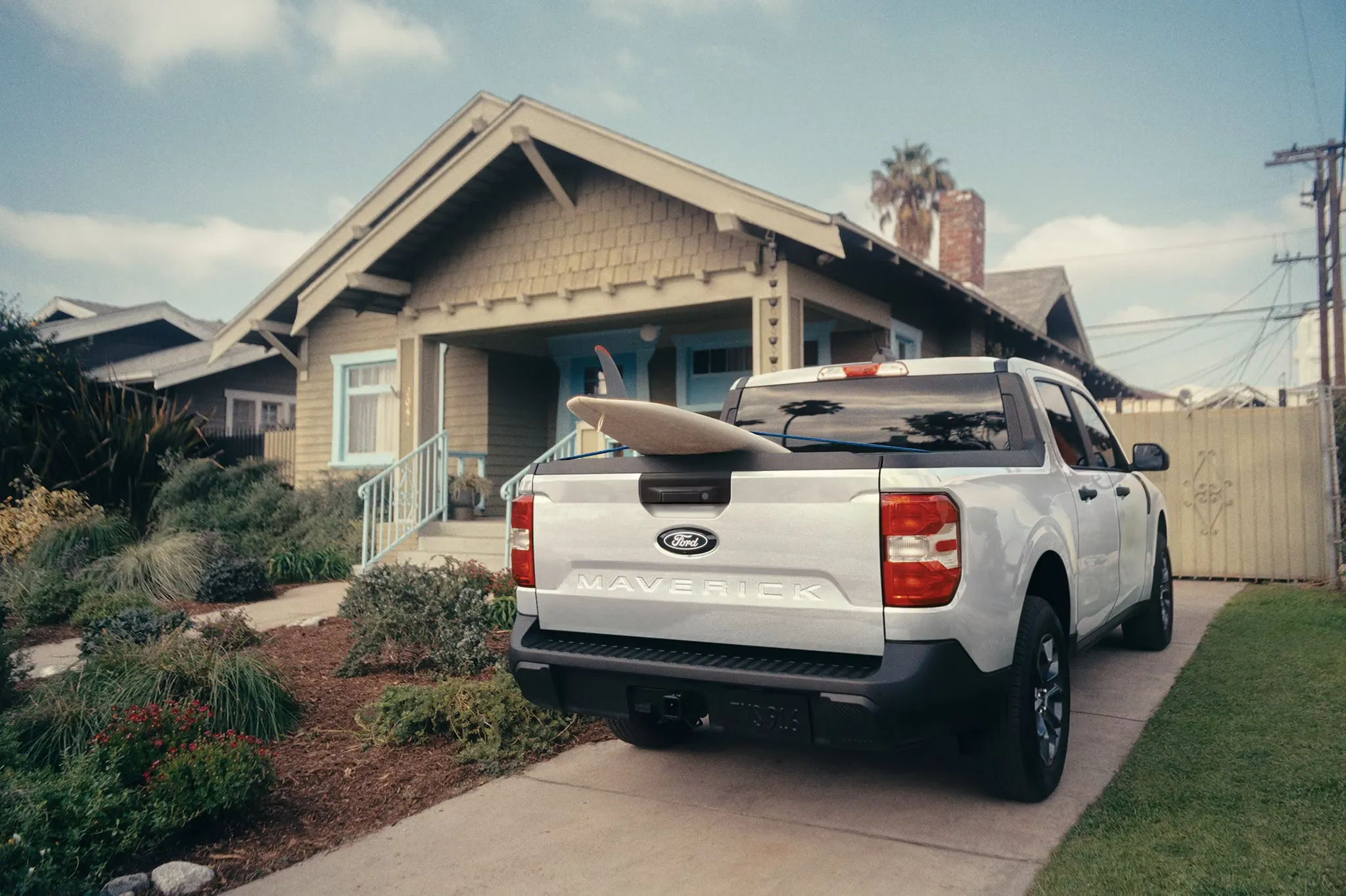 Ford Maverick 2026 blanc avec une planche de surf dans sa caisse.