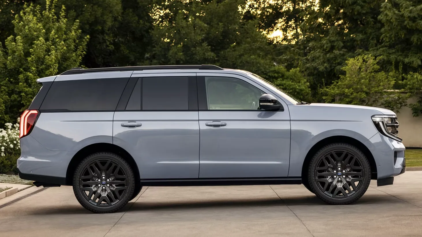 Ford Expedition 2027 gris bleuté en vue trois quarts avant, devant un décor de verdure.