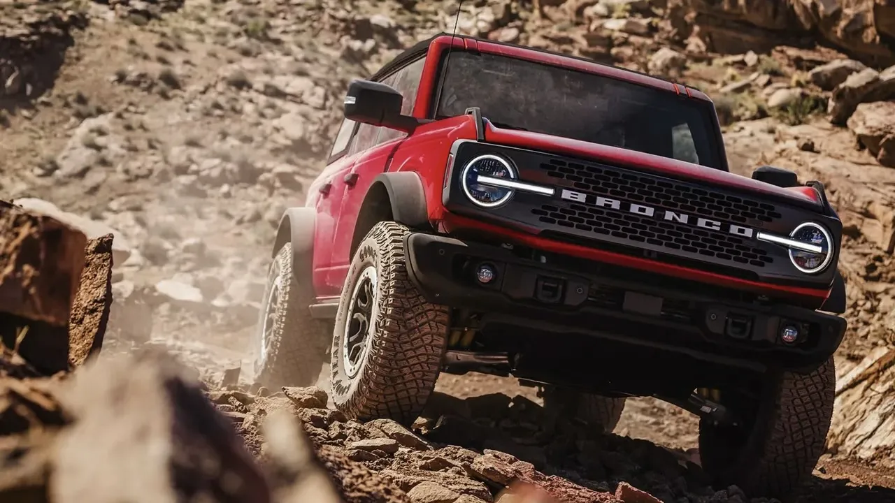 Ford Bronco 2026 rouge roulant sur un terrain rocailleux hors route.