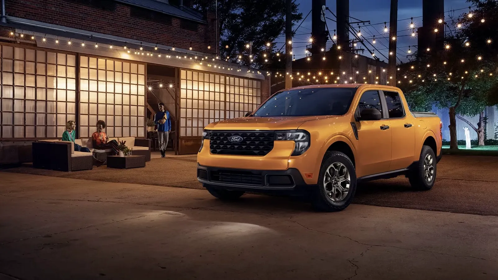 Ford Maverick 2026 orange devant un bâtiment illuminé au crépuscule.