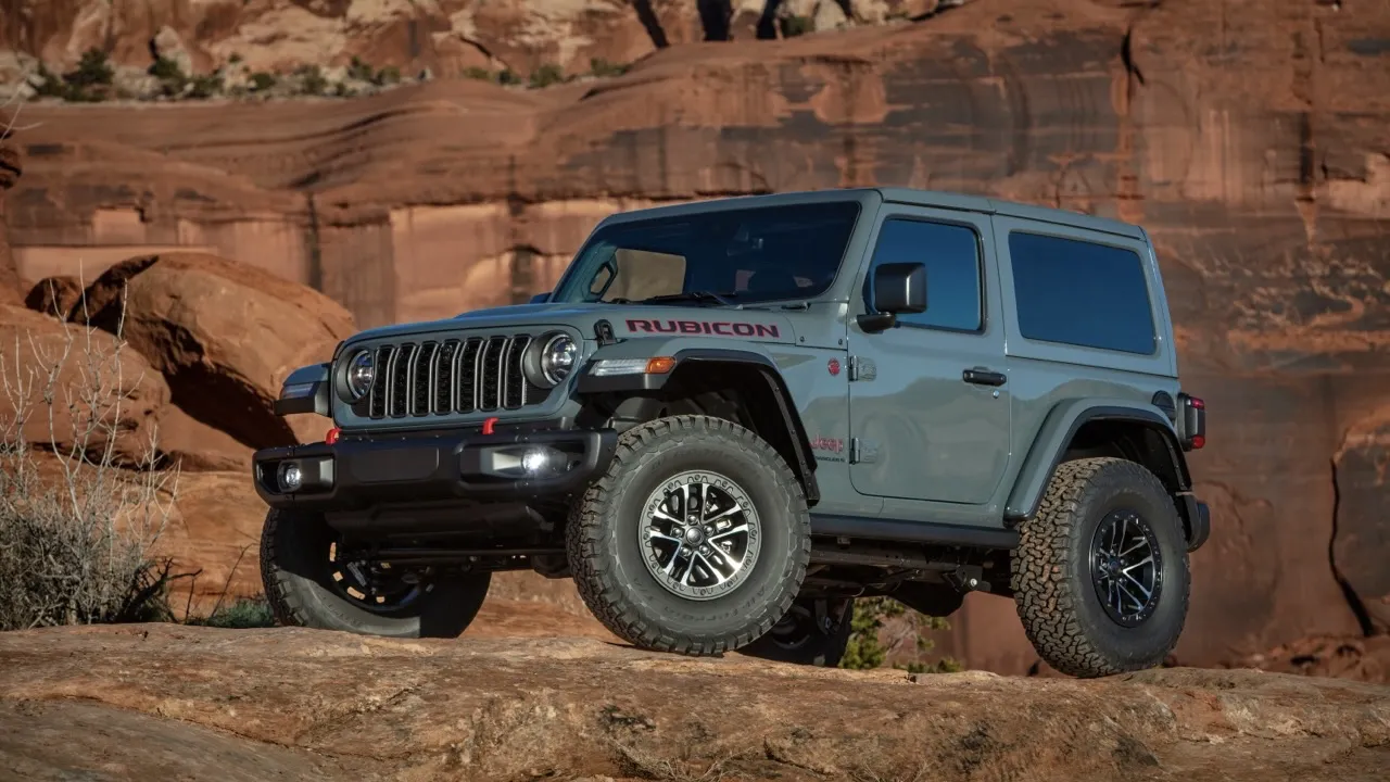 Jeep Wrangler 2026 gris en vue trois quarts avant, sur un terrain rocailleux.